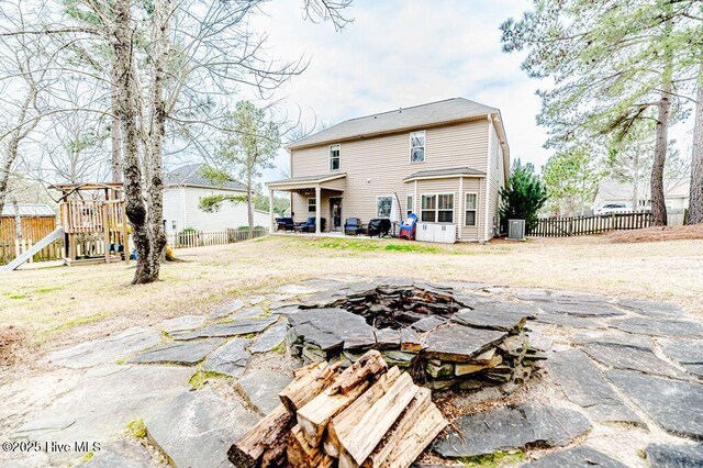 back of house featuring a fenced backyard, a fire pit, a playground, and a patio