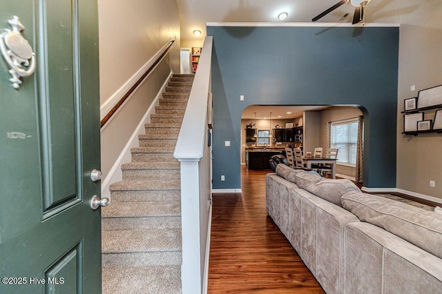 interior space featuring baseboards, wood finished floors, arched walkways, and ceiling fan