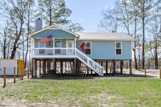 view of front facade with a front lawn, a porch, fence, stairway, and a chimney