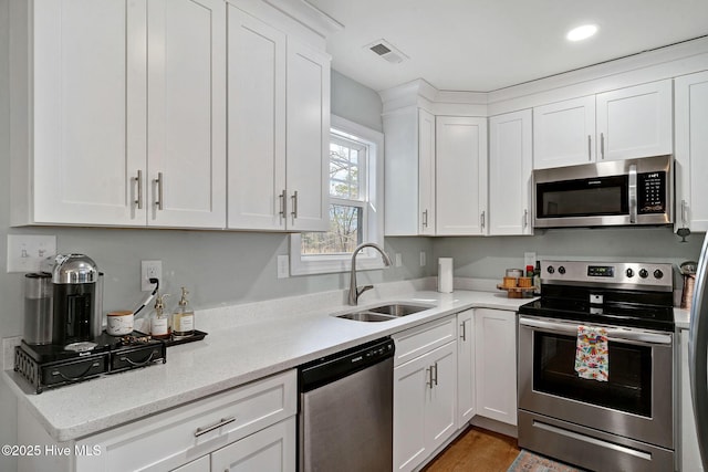 kitchen with a sink, visible vents, appliances with stainless steel finishes, and white cabinets