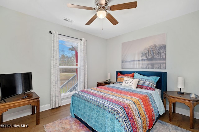 bedroom with ceiling fan, visible vents, baseboards, and wood finished floors