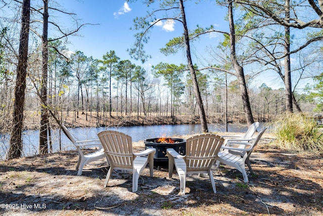 view of yard with a fire pit, a forest view, and a water view