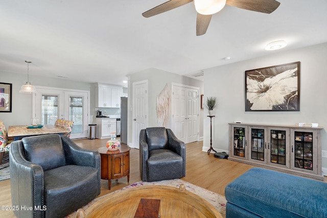 living area with light wood finished floors, ceiling fan, french doors, and baseboards