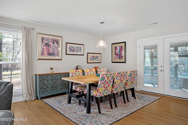 dining area with french doors, visible vents, and wood finished floors