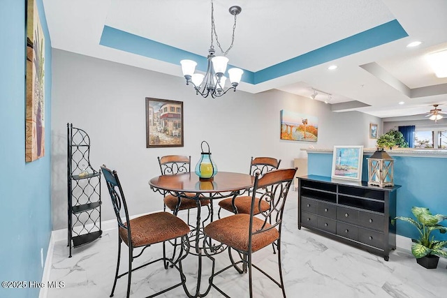 dining room with baseboards, recessed lighting, a raised ceiling, ceiling fan with notable chandelier, and marble finish floor