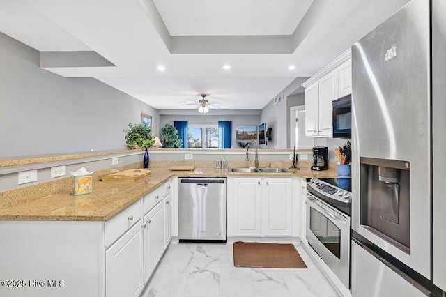 kitchen featuring marble finish floor, a sink, recessed lighting, appliances with stainless steel finishes, and a raised ceiling