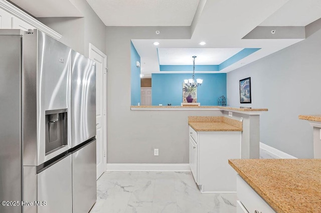 kitchen with baseboards, an inviting chandelier, stainless steel refrigerator with ice dispenser, white cabinetry, and marble finish floor