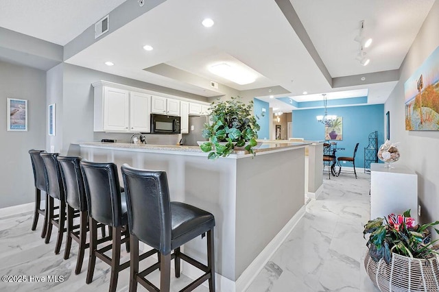 kitchen featuring visible vents, baseboards, a tray ceiling, and black microwave