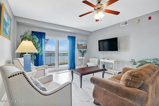 living area with a ceiling fan, visible vents, and marble finish floor