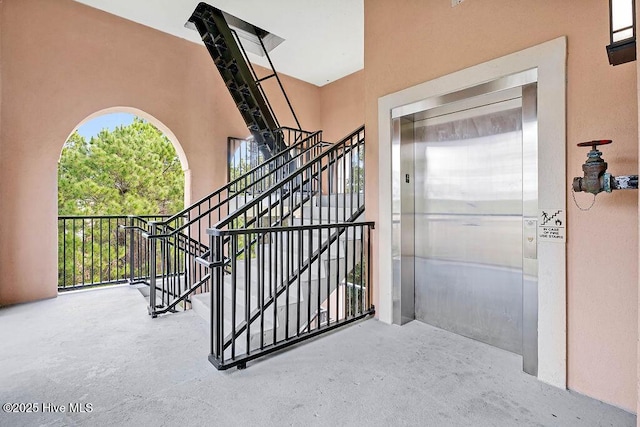 exterior space with elevator, unfinished concrete floors, and stairs