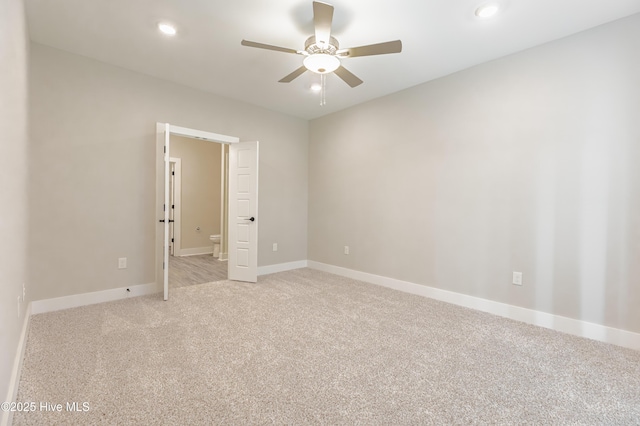 unfurnished room with light colored carpet, a ceiling fan, and baseboards