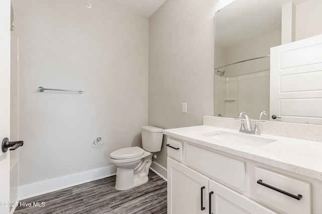 bathroom with toilet, wood finished floors, a shower, baseboards, and vanity