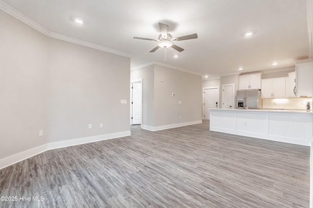 unfurnished living room with ceiling fan, baseboards, light wood-style flooring, and crown molding