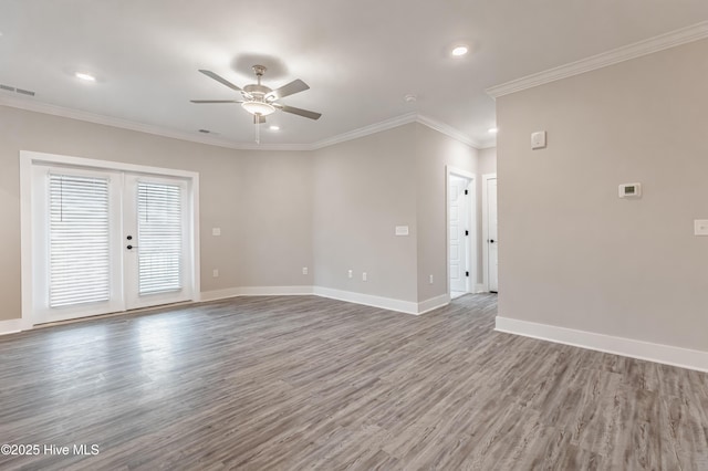 spare room featuring a ceiling fan, wood finished floors, baseboards, visible vents, and crown molding