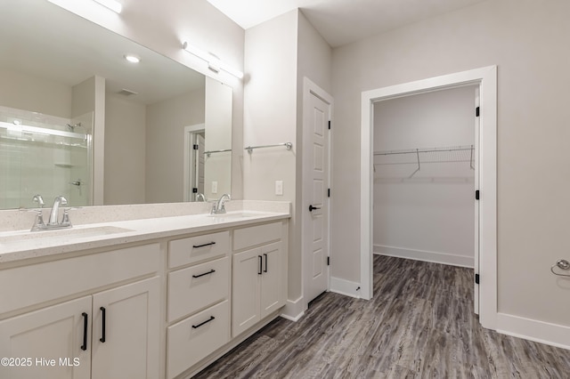 bathroom featuring a shower stall, wood finished floors, baseboards, and a sink