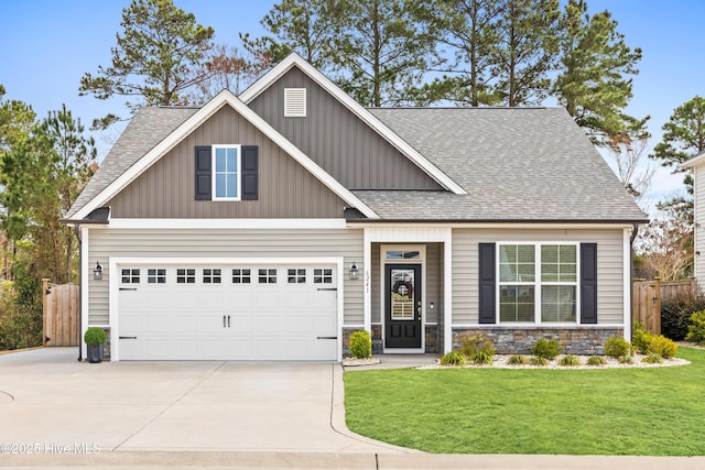 craftsman-style house with a front lawn, concrete driveway, a garage, and fence