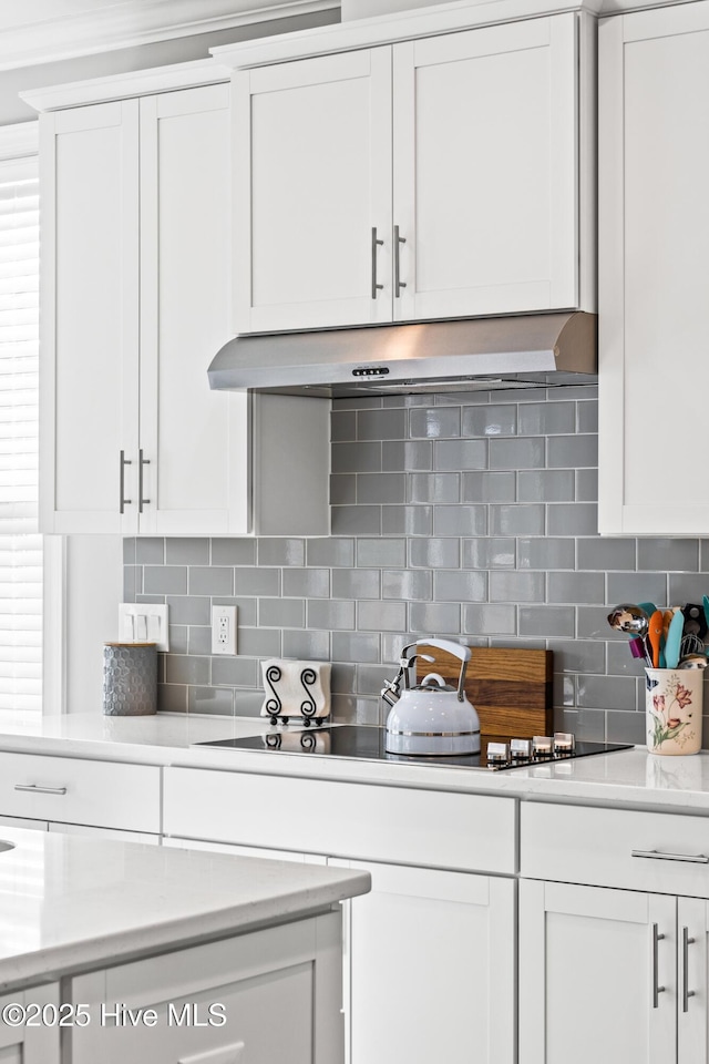 kitchen featuring light countertops, white cabinets, and under cabinet range hood