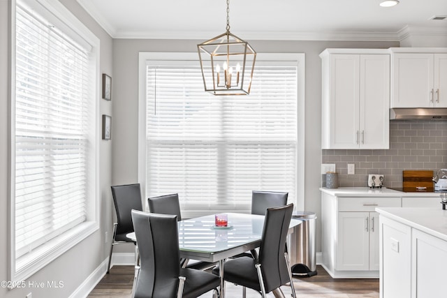 dining area with an inviting chandelier, wood finished floors, baseboards, and ornamental molding