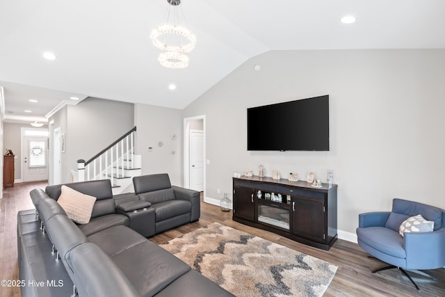 living area featuring wood finished floors, baseboards, stairs, vaulted ceiling, and a notable chandelier