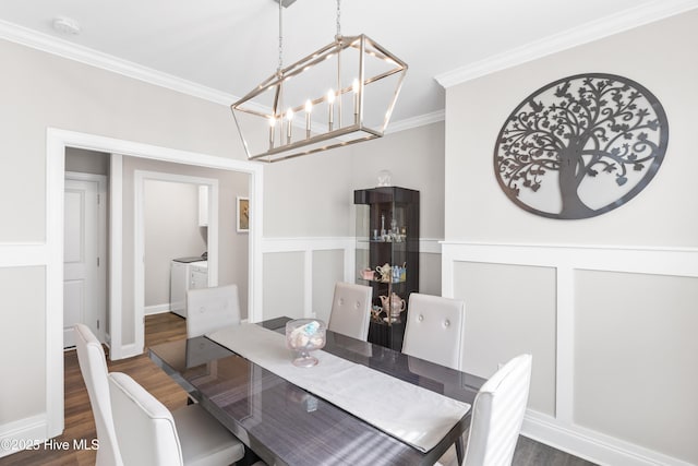 dining space featuring a notable chandelier, washing machine and dryer, ornamental molding, and wood finished floors