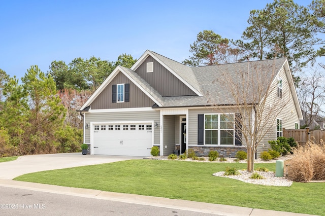 craftsman-style home featuring a shingled roof, a front lawn, fence, concrete driveway, and stone siding