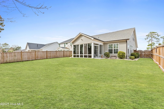 back of house with a lawn, a shingled roof, a fenced backyard, and a sunroom