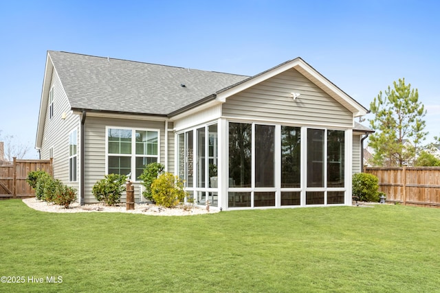 back of house with a lawn, fence, roof with shingles, and a sunroom