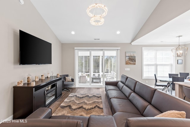 living room featuring plenty of natural light, lofted ceiling, an inviting chandelier, and wood finished floors