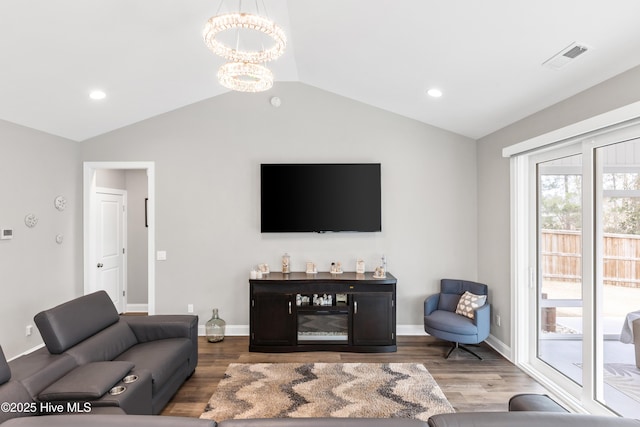 living area featuring lofted ceiling, a notable chandelier, wood finished floors, and visible vents