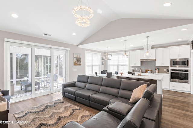 living area with wood finished floors, visible vents, an inviting chandelier, lofted ceiling, and recessed lighting