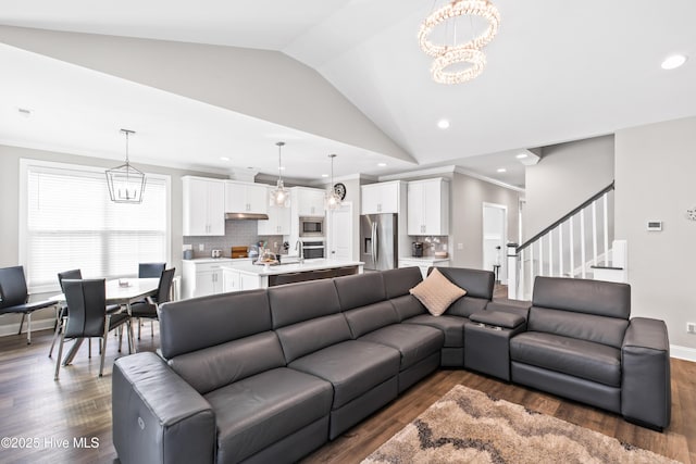 living room with vaulted ceiling, a notable chandelier, crown molding, and dark wood-type flooring