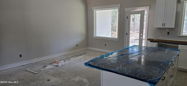 kitchen with a kitchen island, white cabinetry, and baseboards