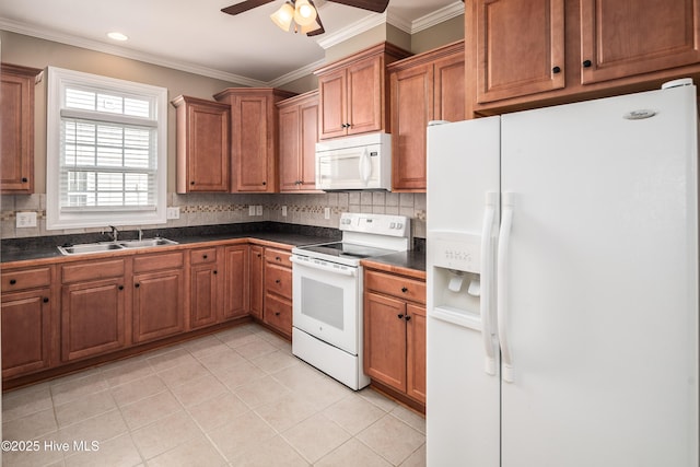 kitchen with white appliances, brown cabinetry, ornamental molding, a sink, and dark countertops