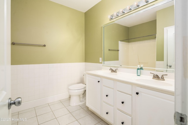 full bathroom with tile patterned floors, toilet, a sink, wainscoting, and double vanity