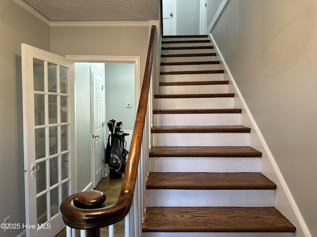 stairway with a textured ceiling and ornamental molding