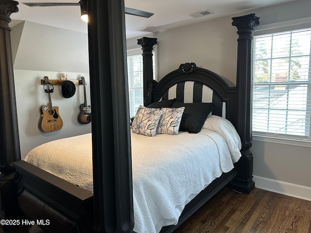 bedroom featuring a ceiling fan, wood finished floors, visible vents, baseboards, and decorative columns