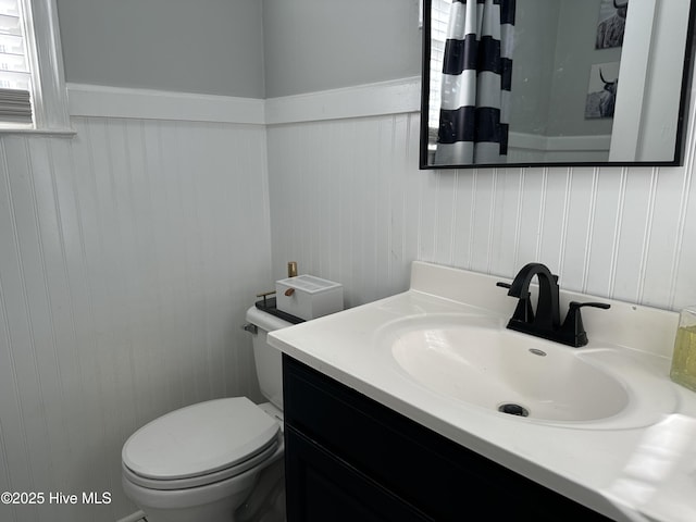 bathroom featuring vanity, toilet, and wainscoting