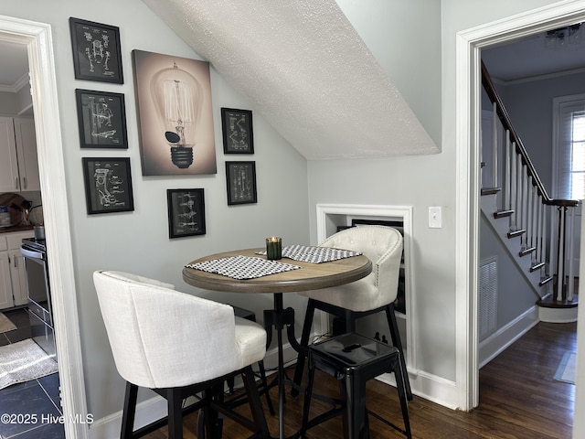 dining area with stairs, dark wood-type flooring, baseboards, and vaulted ceiling