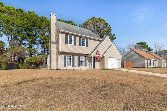 colonial inspired home with an attached garage, concrete driveway, a chimney, and a front lawn