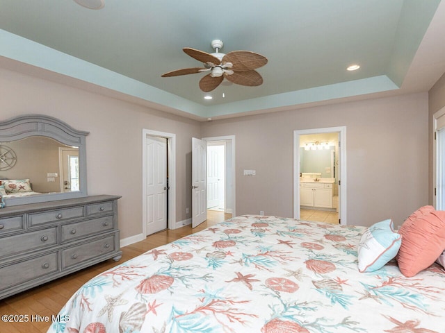129 Sunset Dr, Cedar Point, NC 28584 - bedroom featuring recessed lighting, connected bathroom, light wood-style flooring, and a tray ceiling