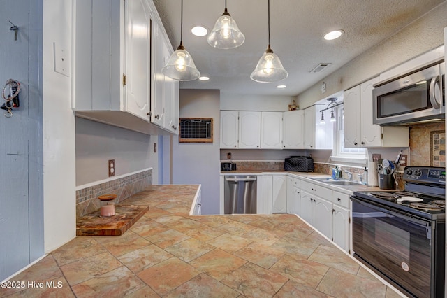 kitchen featuring visible vents, a sink, appliances with stainless steel finishes, white cabinets, and light countertops