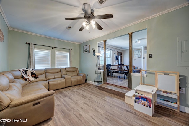 living room with a ceiling fan, baseboards, visible vents, light wood-style flooring, and ornamental molding