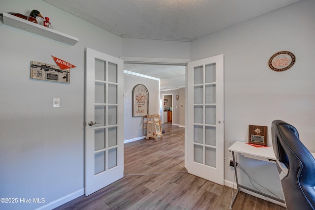 office with french doors, baseboards, a textured ceiling, and wood finished floors