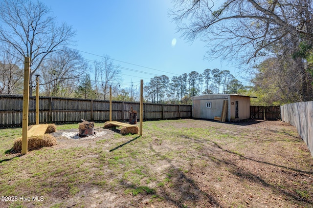 view of yard featuring an outdoor structure, a fenced backyard, a shed, and a fire pit