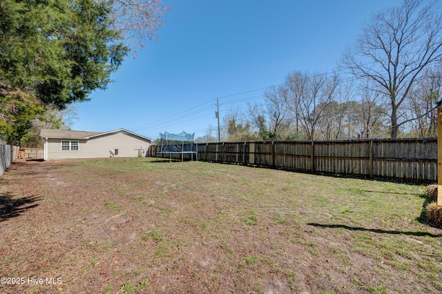 view of yard featuring a trampoline and a fenced backyard