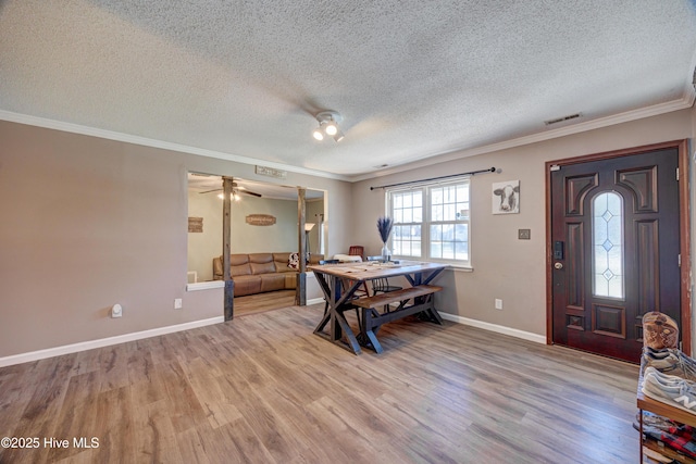 foyer featuring visible vents, ornamental molding, and wood finished floors