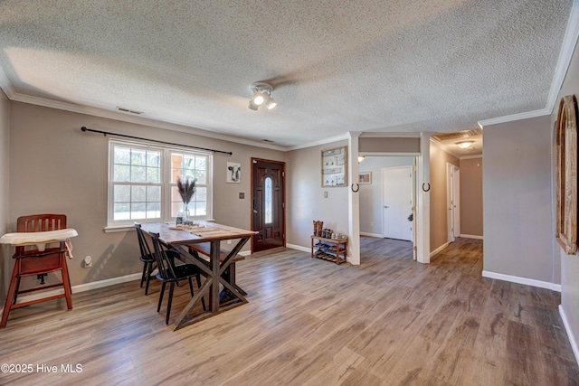 dining room with visible vents, baseboards, crown molding, and light wood finished floors