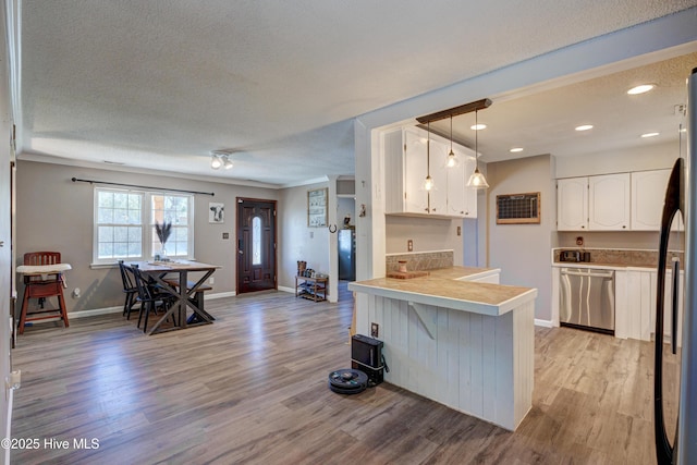 kitchen with light wood-style flooring, appliances with stainless steel finishes, a peninsula, and white cabinets