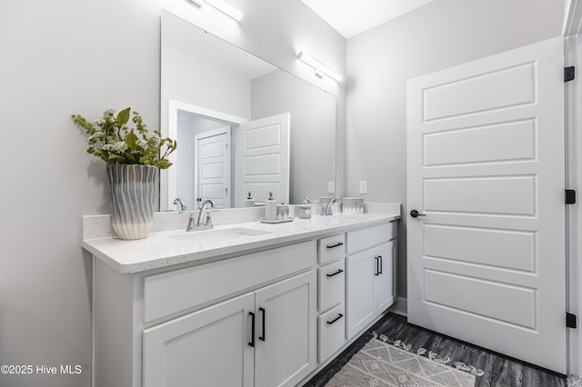 full bath with double vanity, wood finished floors, and a sink
