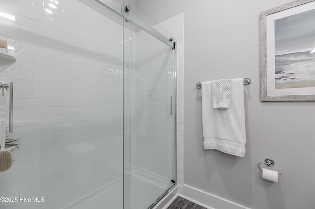 full bath featuring a shower stall and baseboards